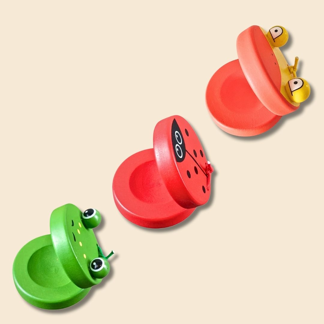 3 single castanets of different animal types: green frog, red ladybug and orange/yellow duck - on a beige background.