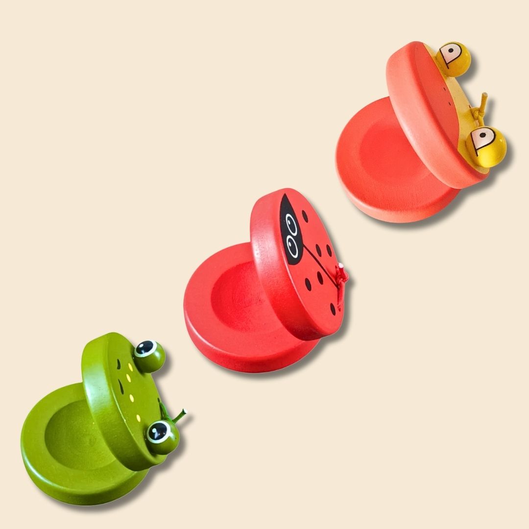 3 single castanets of different animal types: green frog, red ladybug and orange/yellow duck - on a beige background.