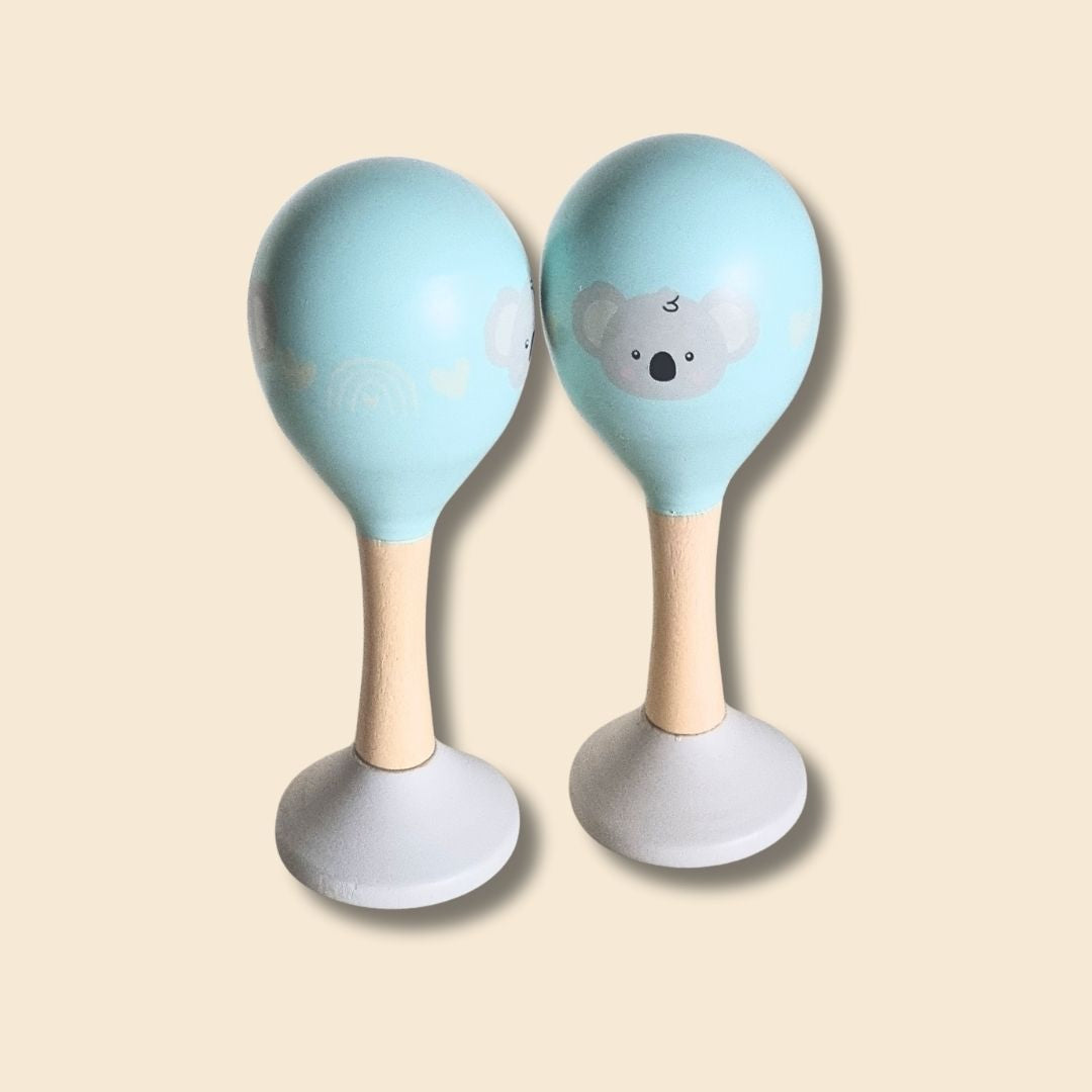 Two baby blue rattles maracas with painted koala design on a beige background