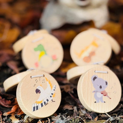 Wooden castanet instruments with animal illustrations on a natural, leafy background