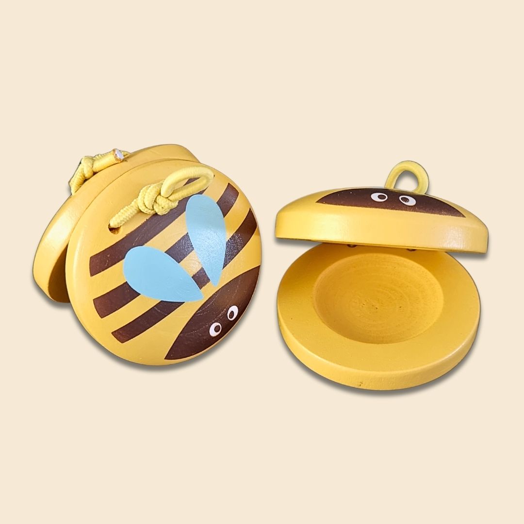 Yellow and brown bee-shaped wooden castanets, showing both sides of the musical instrument on a beige background