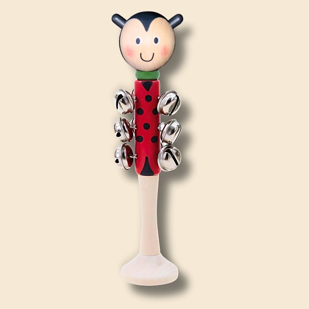 Red and black head, spotted ladybug wooden bell stick instrument on a beige background