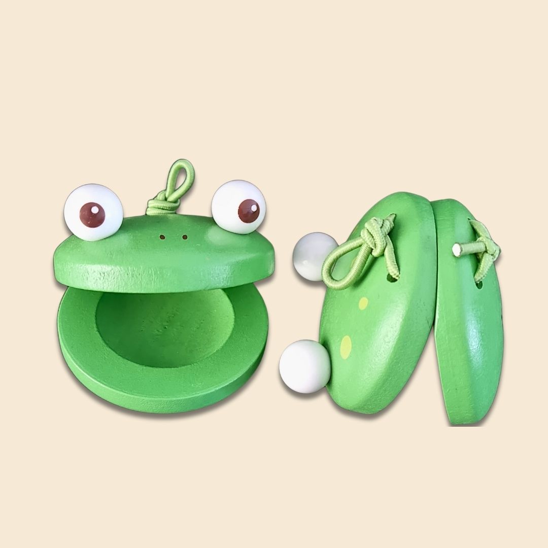 Green wooden frog-shaped castanet set of 2, with googly eyes on a beige background