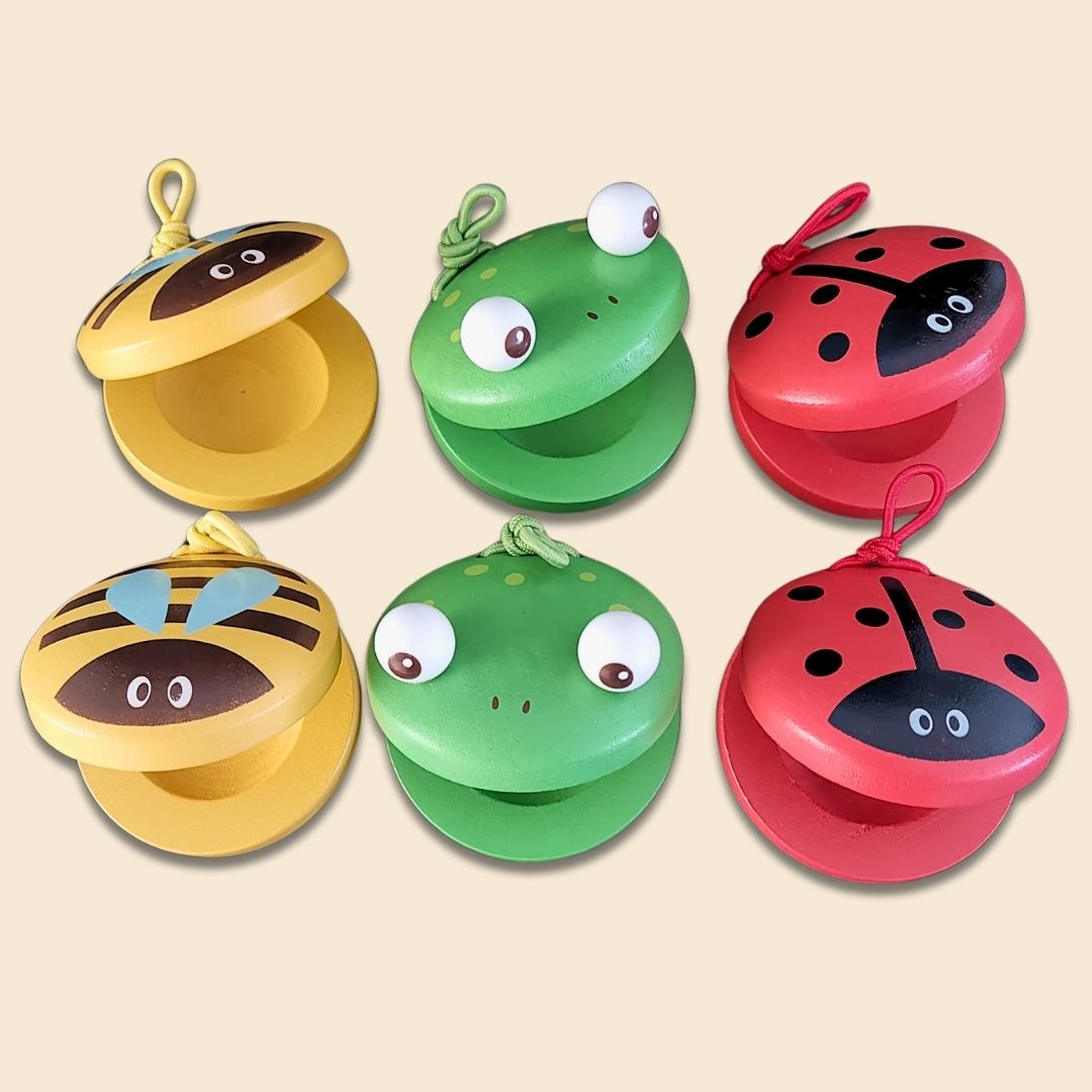 Set of colourful children's musical toys, castanets, shaped like animals on a beige background - Bees, Frogs and Ladybugs