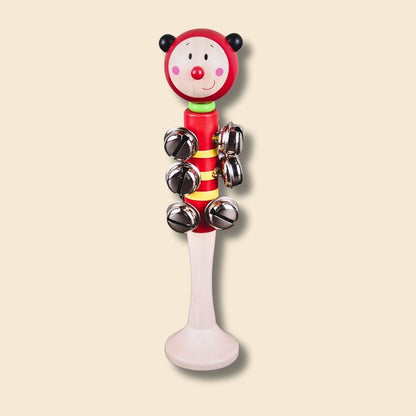 Red ladybug jingle stick, with a red nose, and silver bells on a beige background