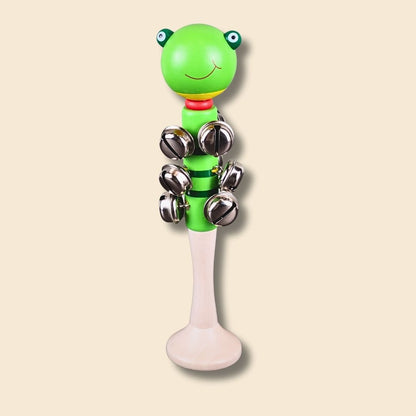 Green frog shaped jingle bell stick with silver bells on a beige background
