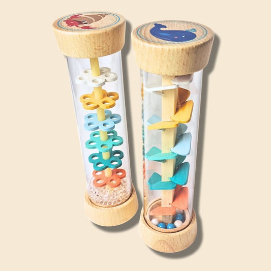 Two colourful wooden rainstick musical toys with transparent tubes and wooden ends on a beige background