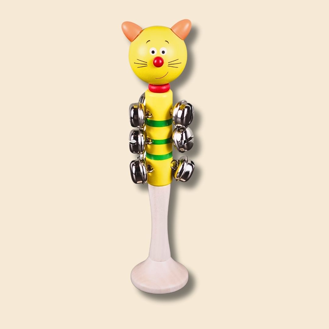 Yellow cat jingle bell stick with smiling face and jingly bells on a beige background